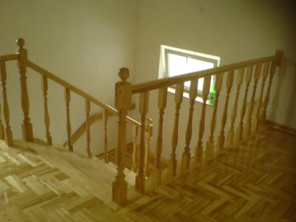 Jasne schody dębowe z toczoną balustradą nad parkietem