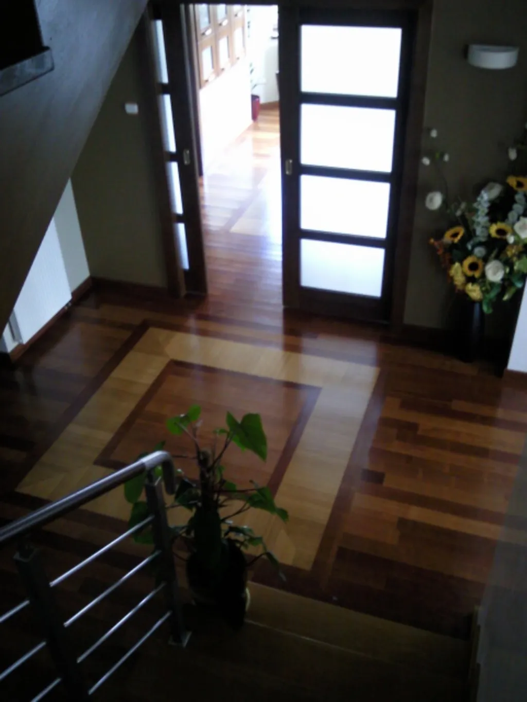 Hol wejściowy z podłogą z intarsją i schodami z balustradą stalową