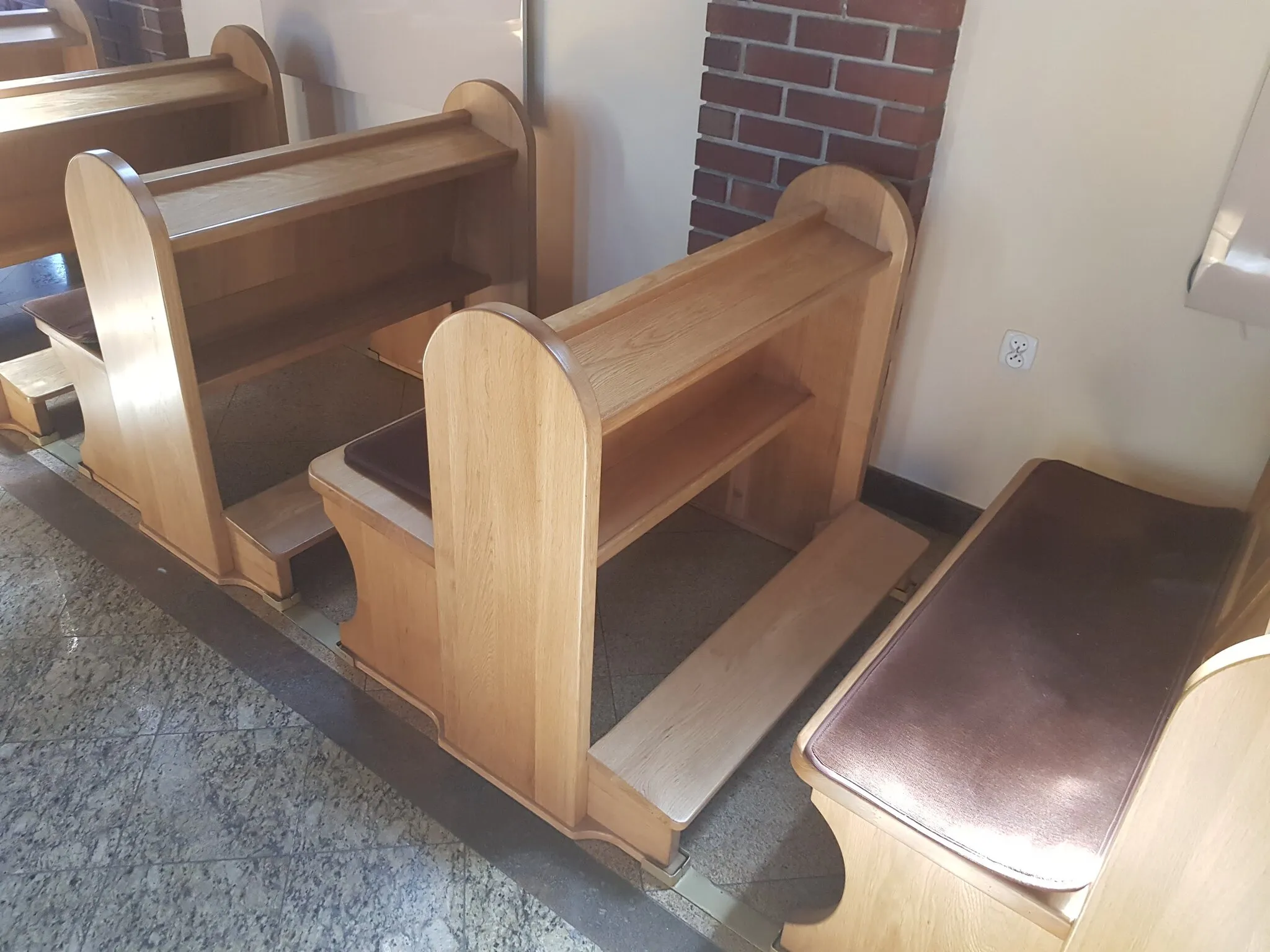 Ławki od tyłu, widoczny pulpit, półka na książki i deska klęcznika