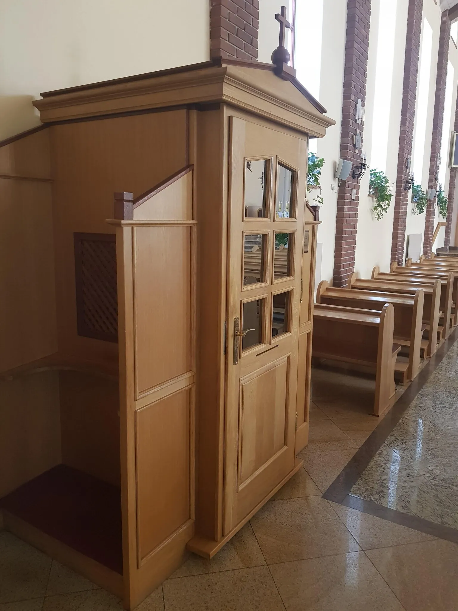 Bok konfesjonału z kratą i ławki ustawione wzdłuż okien w tle